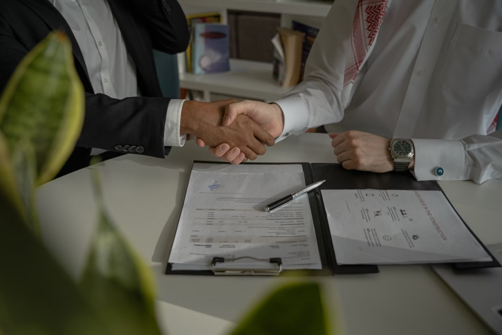 Two business professionals shaking hands across a desk