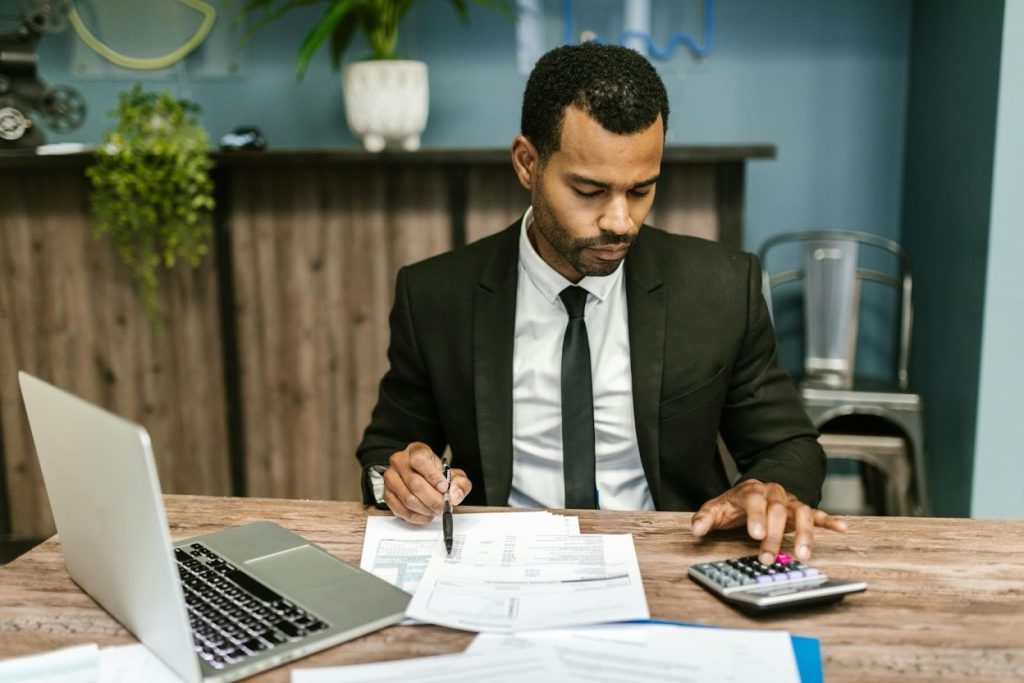 Finance manager organizing contracts and financial documents on a desk with a laptop