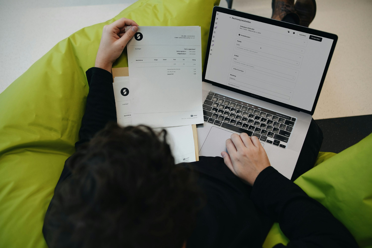Professional reviewing invoices and financial data on a laptop