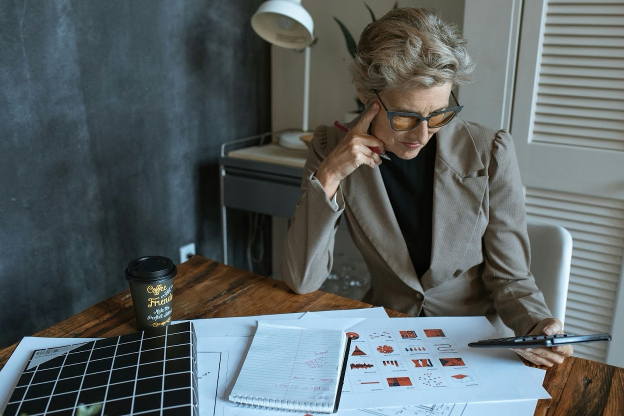 Small business owner reviewing unpaid invoices and financial documents at the desk