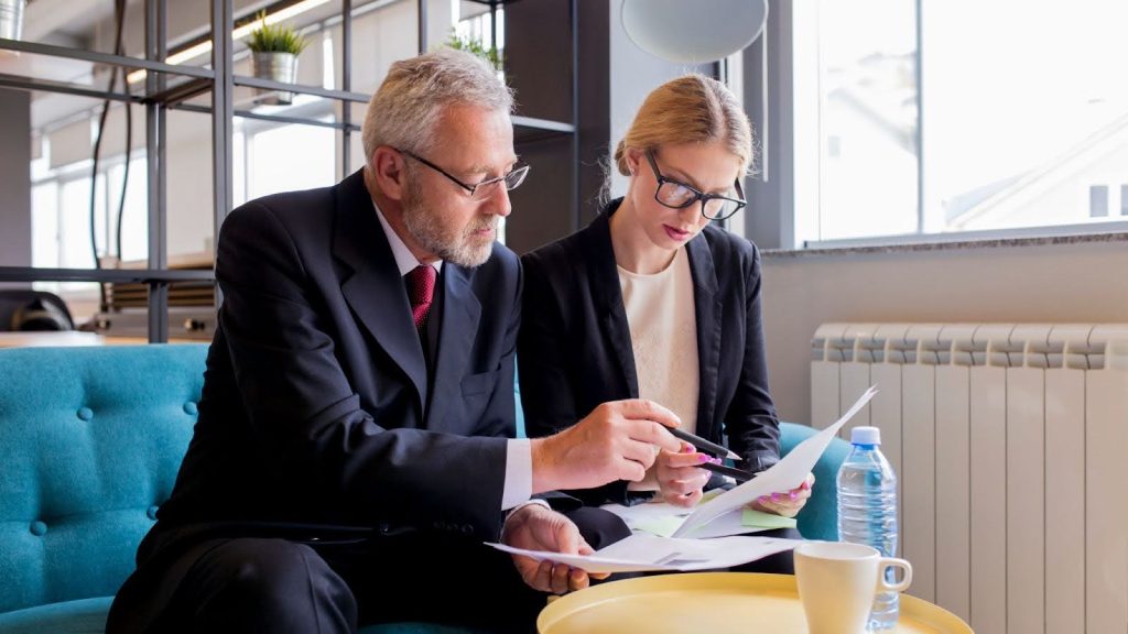 Business meeting with two professionals reviewing settlement documents and contracts.